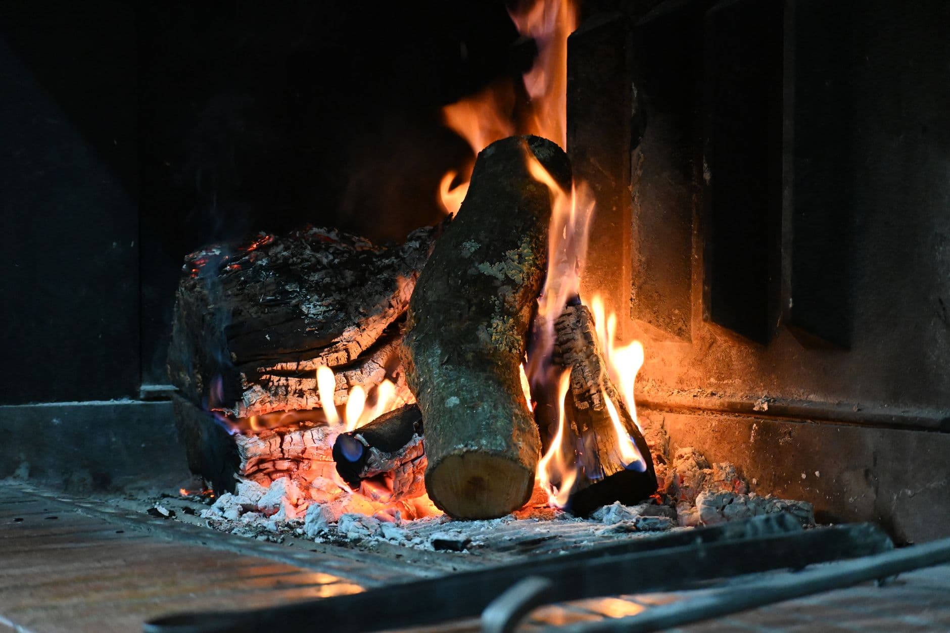 Warm indoor scene of a fireplace with firewood burning brightly, creating a cozy atmosphere.