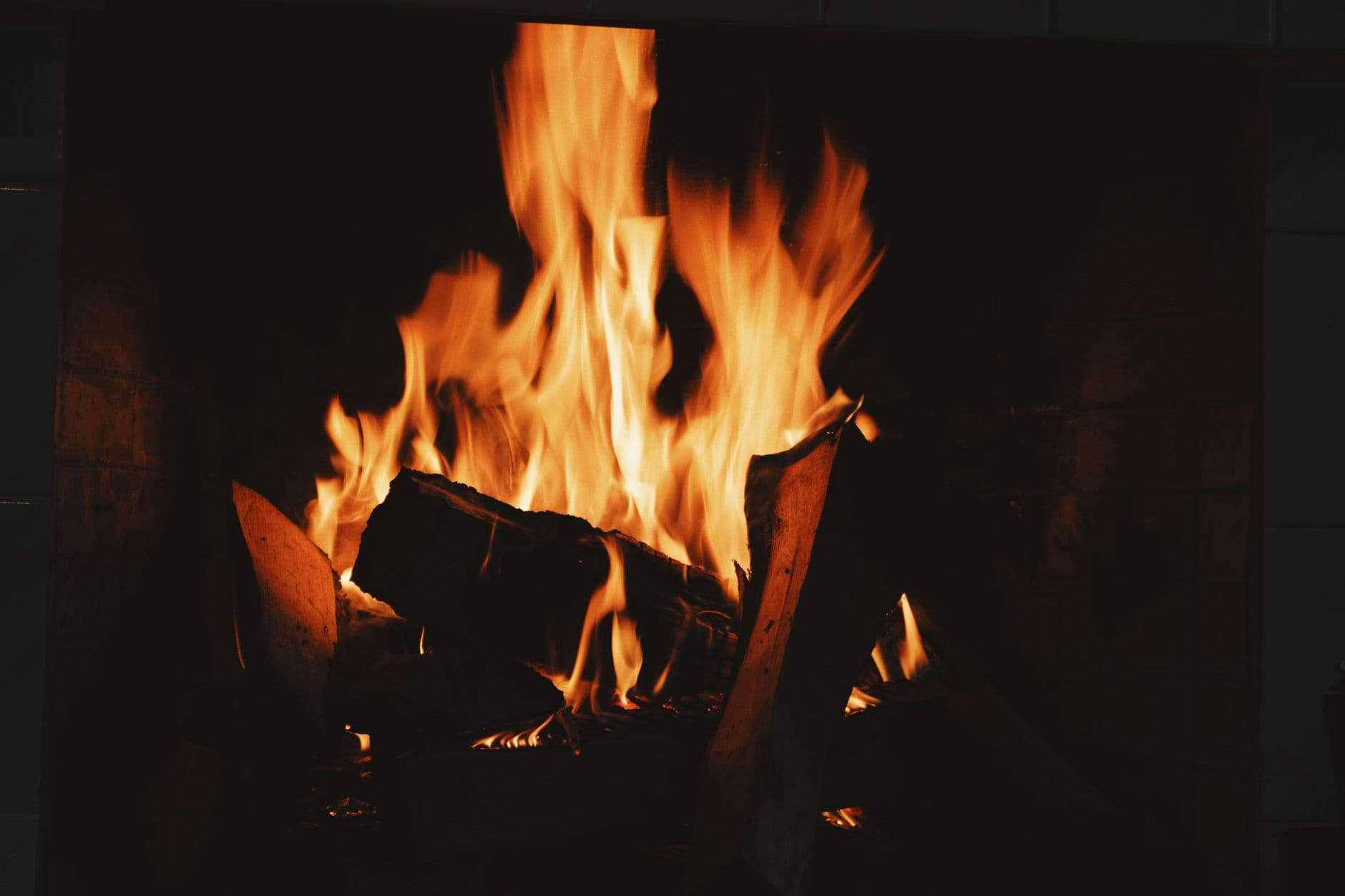 A cozy and warm close-up of a fireplace with crackling flames and firewood. Ideal for winter warmth concepts.